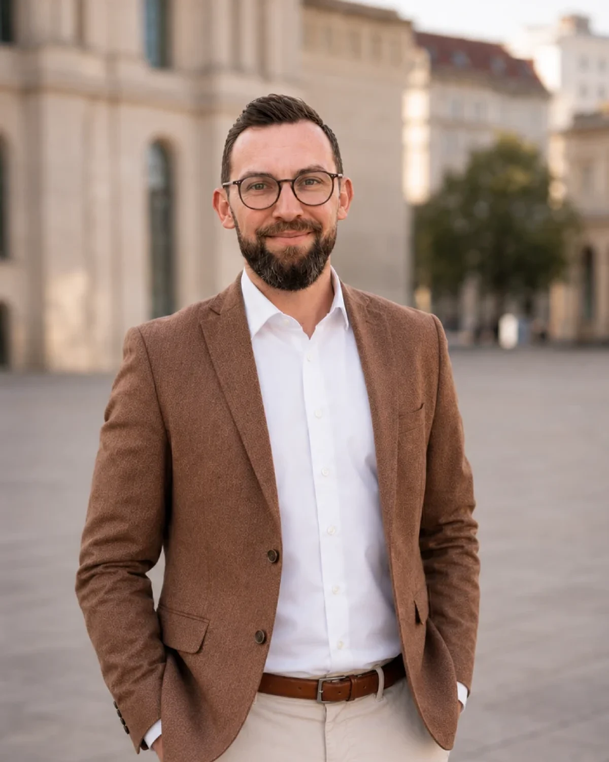 Steven Sabet im braunen Sakko draußen vor heller Architektur